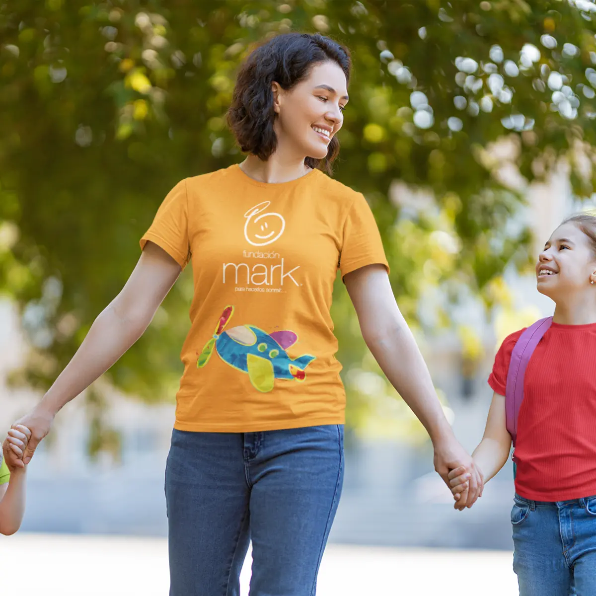 Mujer con playera amarilla sonriendo en un parque junto a un niño, representando las actividades comunitarias de Fundación Mark.