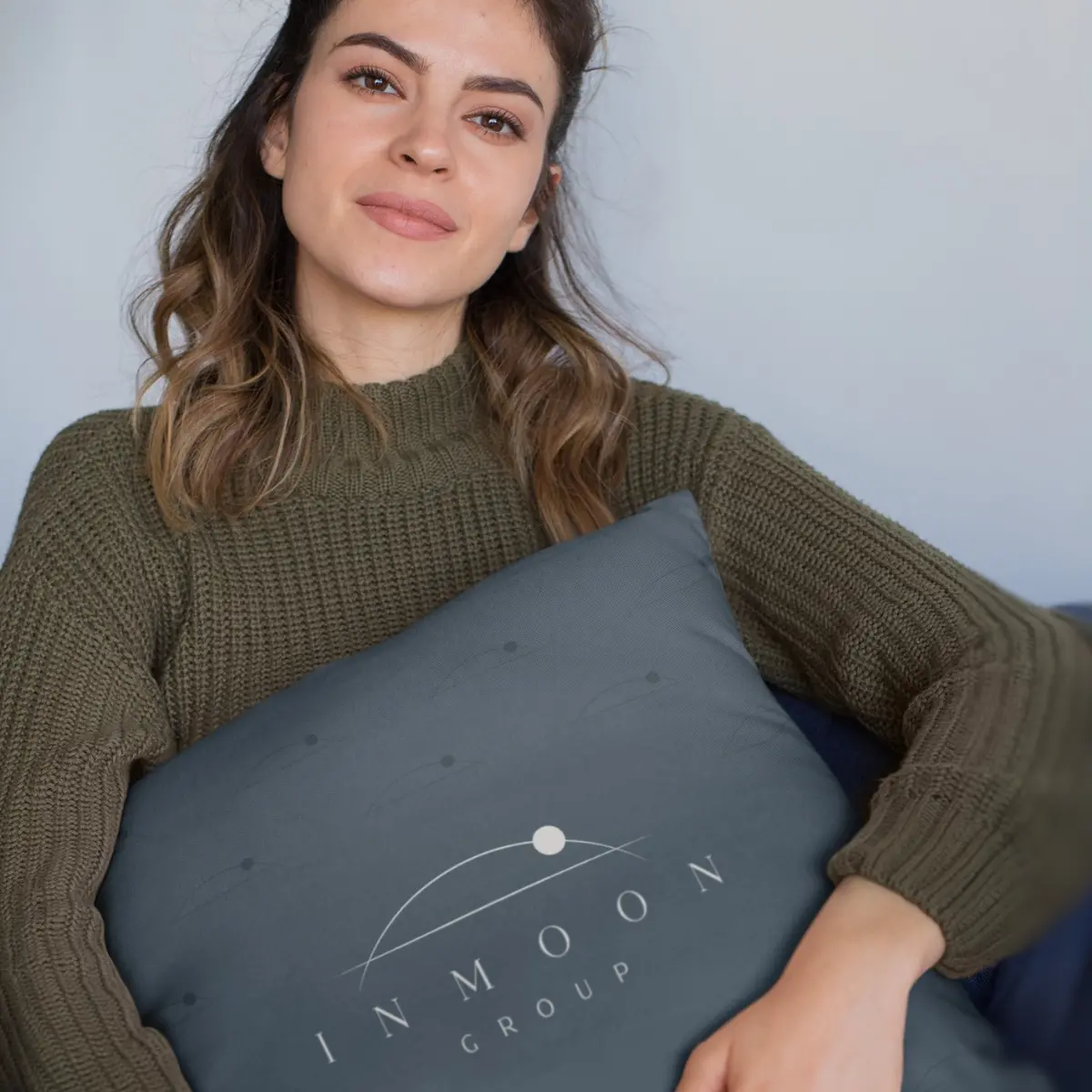 Mujer joven sosteniendo una laptop cerrada bajo el brazo y sonriendo con confianza para la marca In Moon.