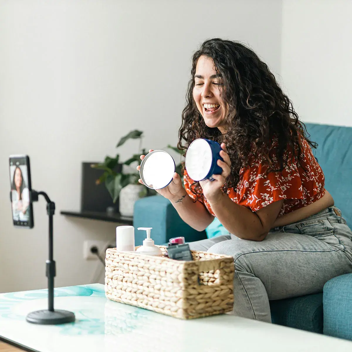 Mujer sonriente transmitiendo en vivo con un aro de luz y su celular, creadora de contenido e influencer digital.