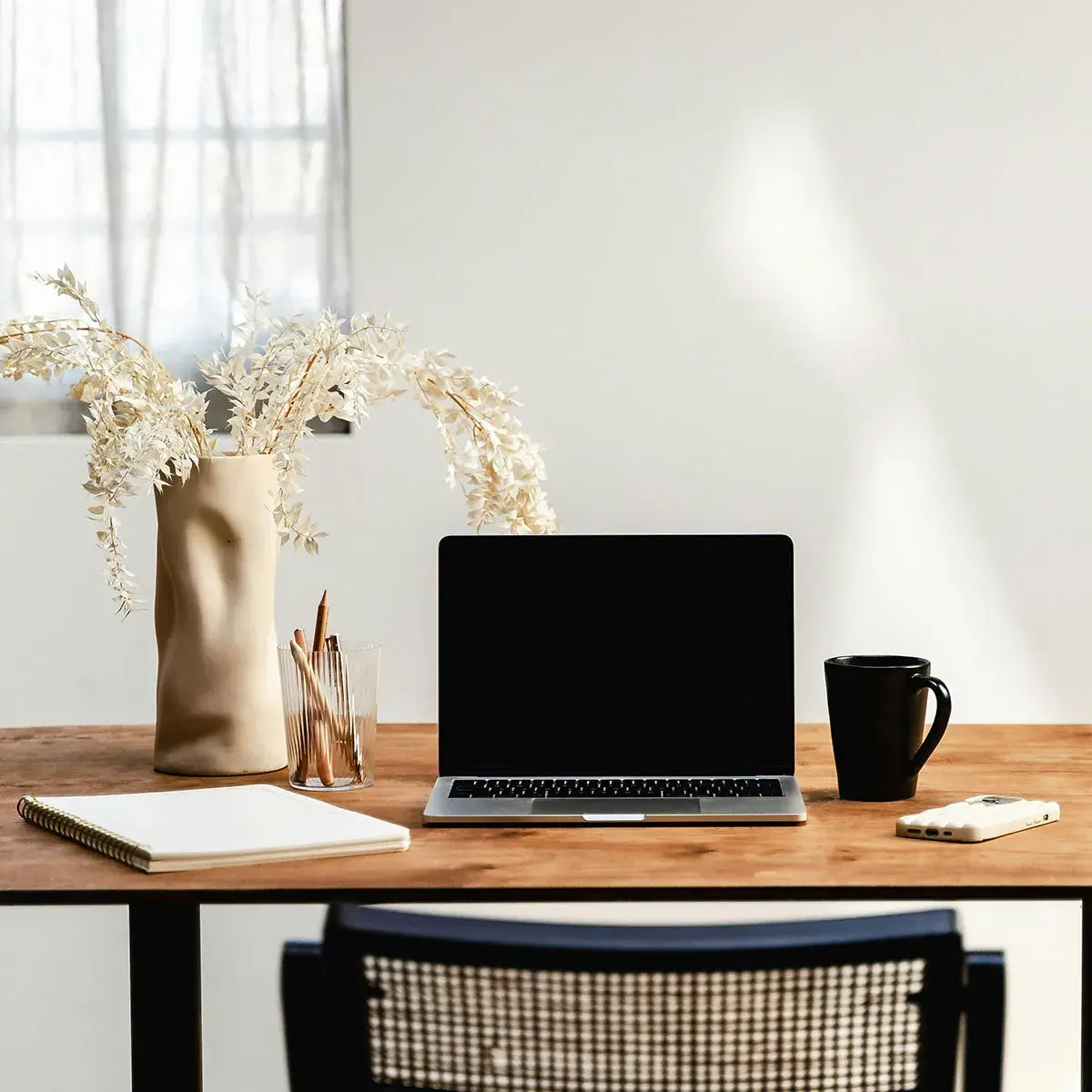 Espacio de trabajo minimalista de home office con laptop abierta, planta decorativa y luz natural para profesionales independientes.