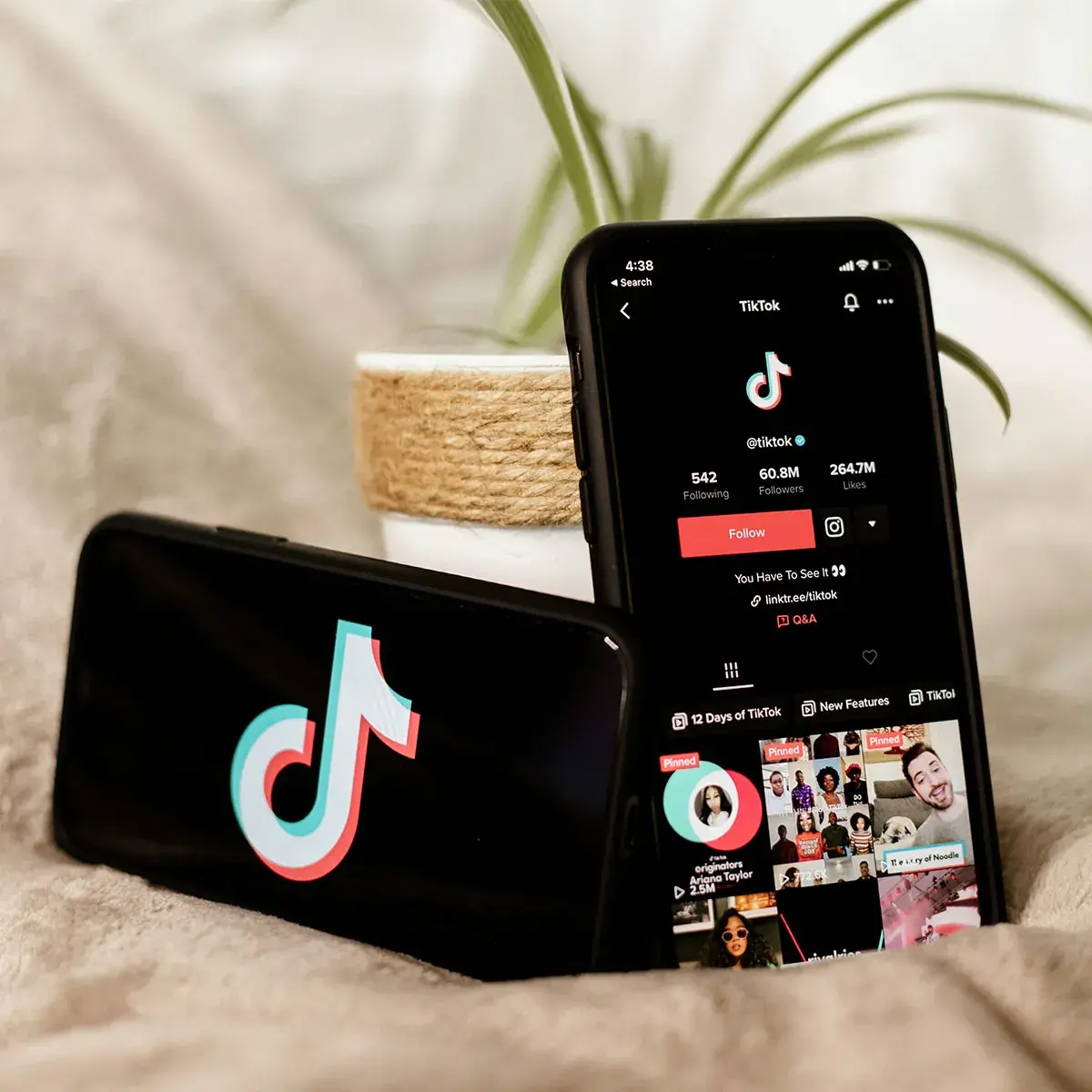 Celular mostrando la aplicación de TikTok junto a audífonos sobre un escritorio de trabajo digital.