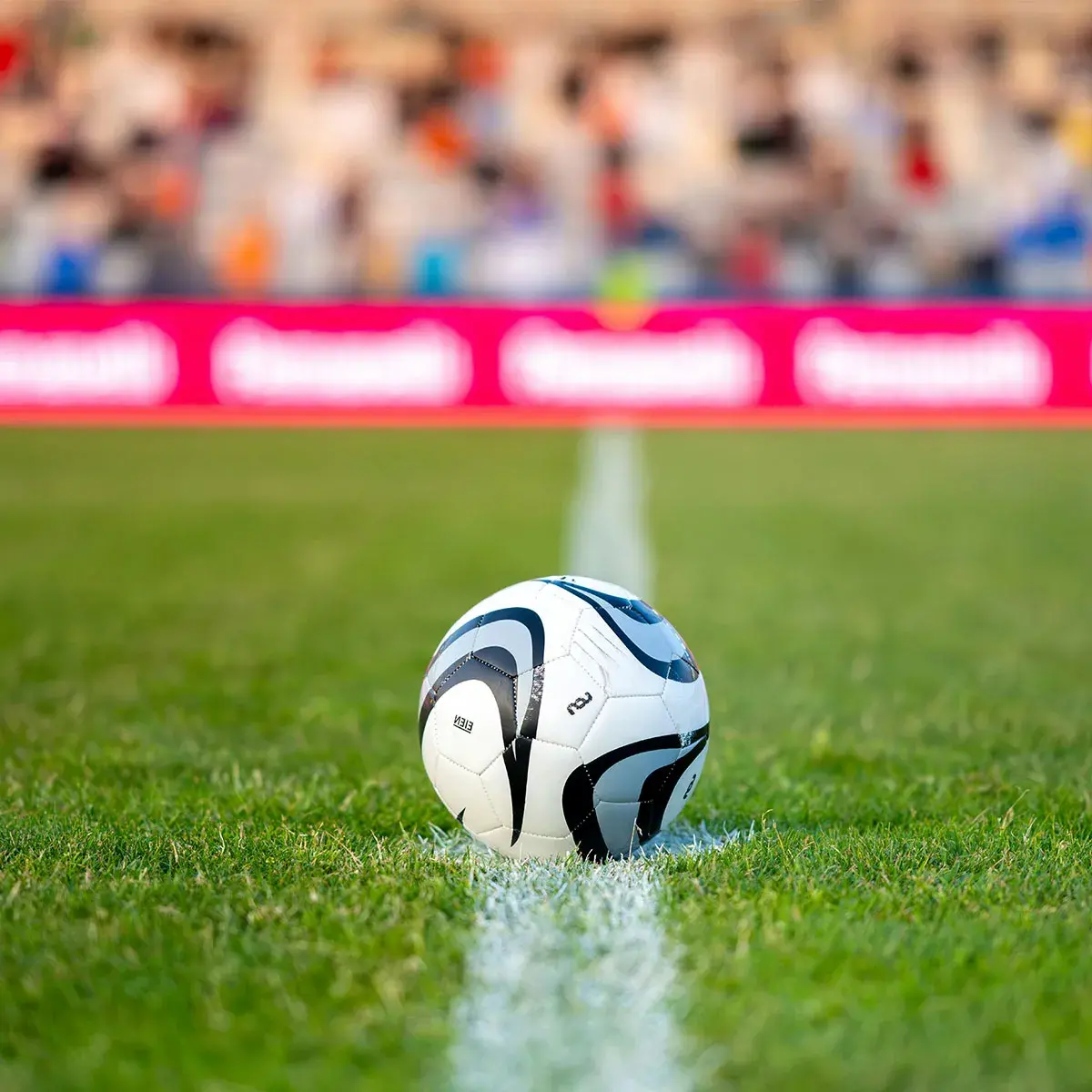 Balón de fútbol sobre el césped de una cancha con estadio de fondo, representación de marketing deportivo legal para el mundial.