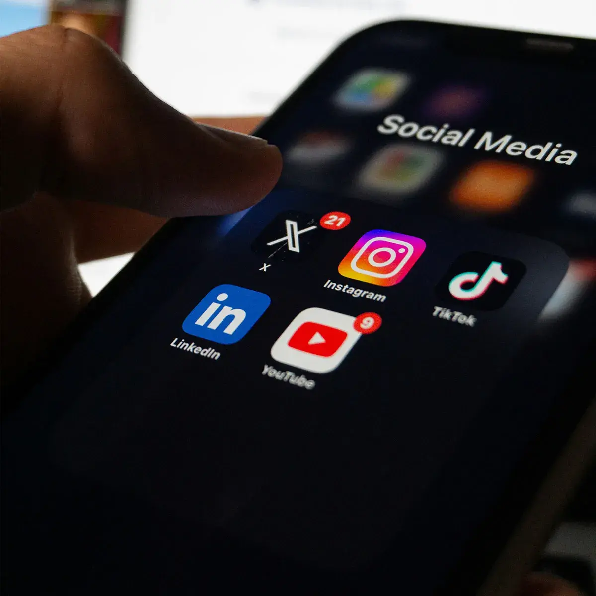 Mano sosteniendo un teléfono con iconos de redes sociales, representando la estrategia de curaduría extrema frente al exceso de contenido.